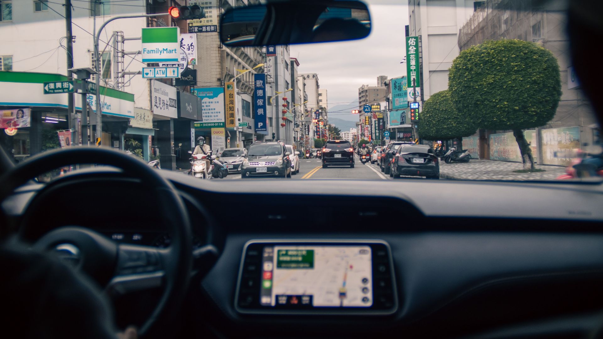 Urban street view captured from inside a car, showcasing city vibrancy and traffic.