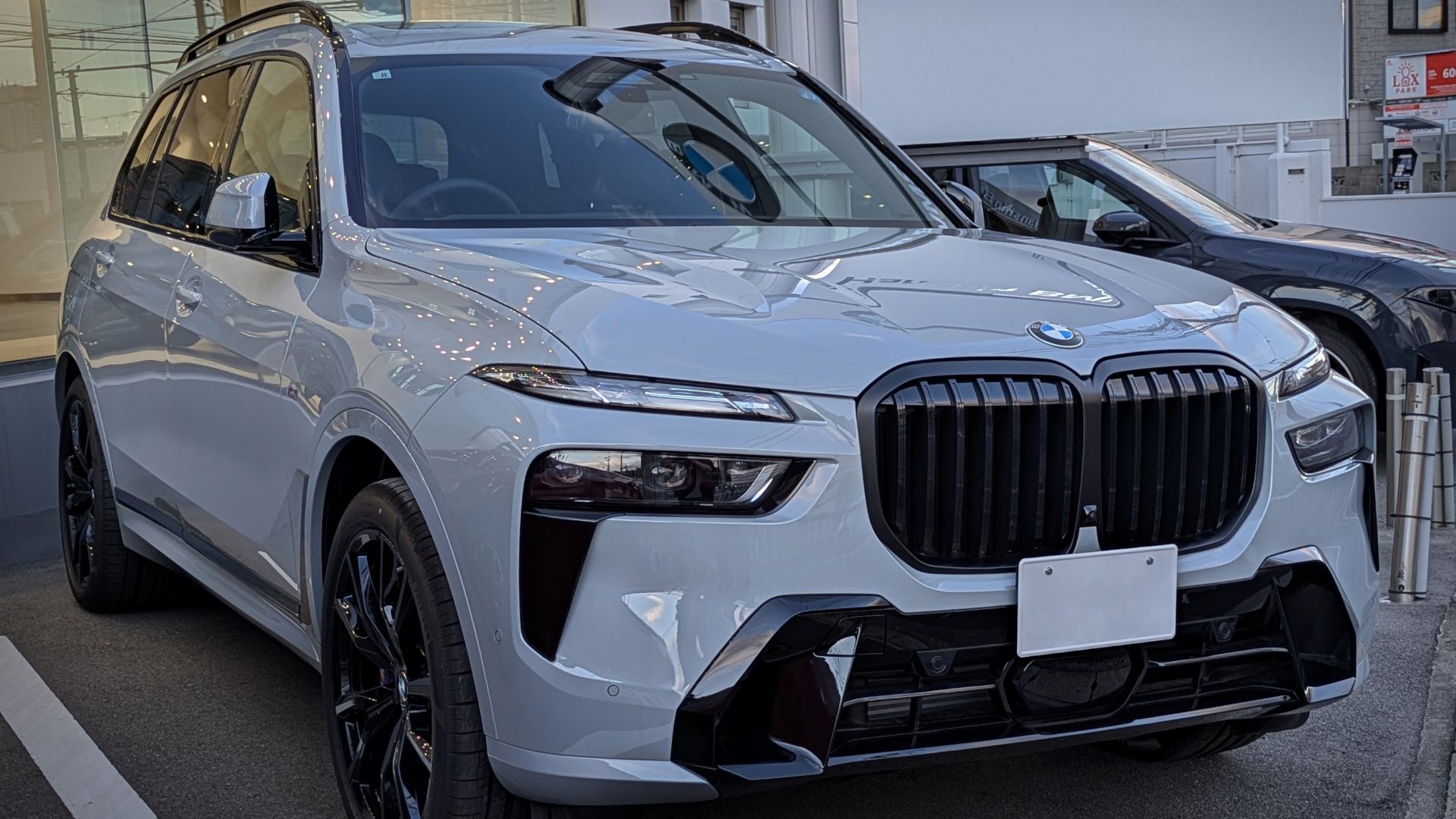A BMW X7 M Sport (Japanese domestic market specification, G07, facelift), photographed in front of an authorized dealer in Osaka Prefecture, Japan.