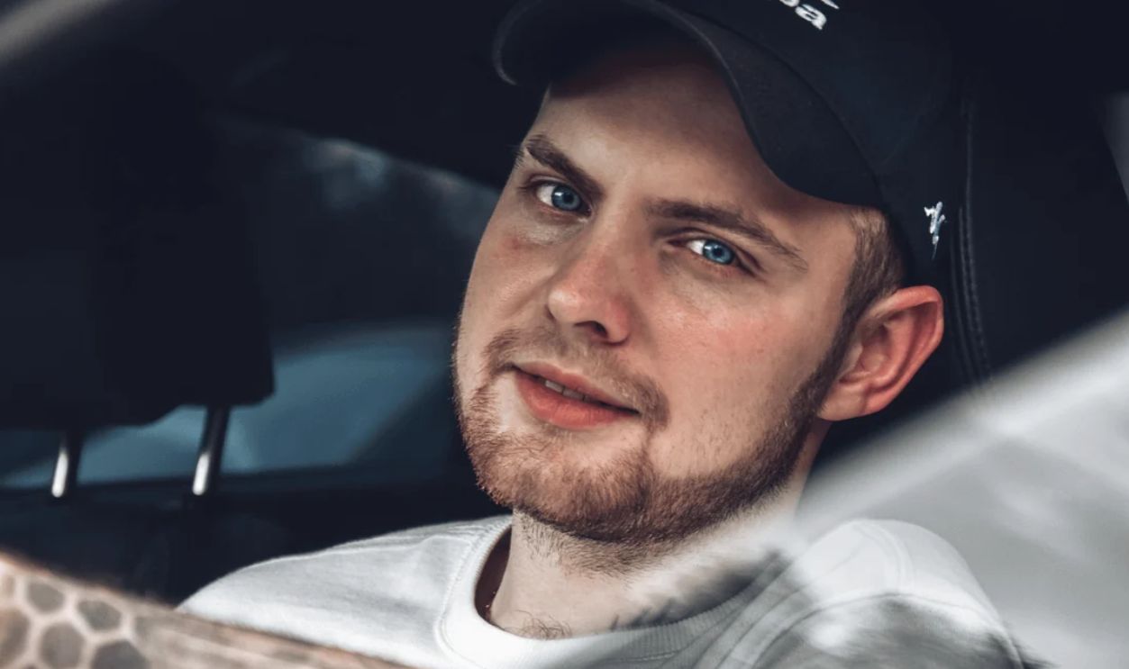 Close-up of a smiling, bearded man with blue eyes sitting in a car, creating a relaxed atmosphere.