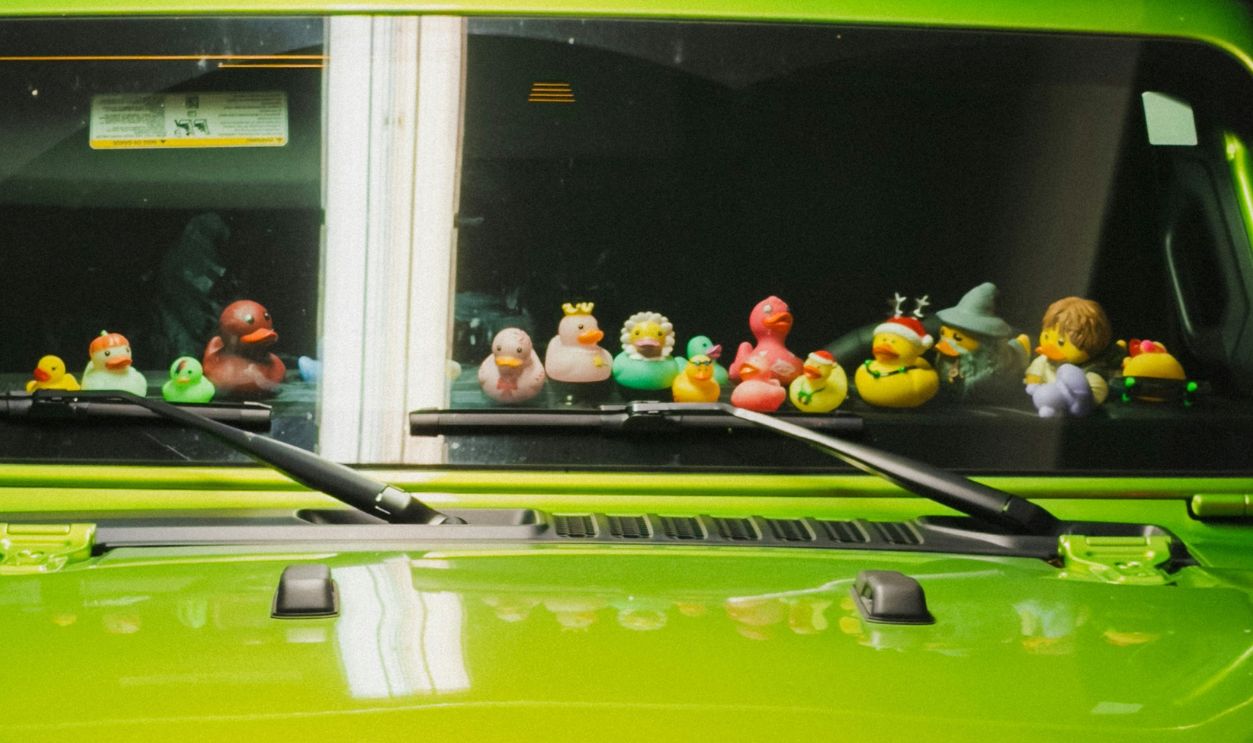 A bright green Jeep decorated with colorful rubber ducks lined across the dashboard at night.