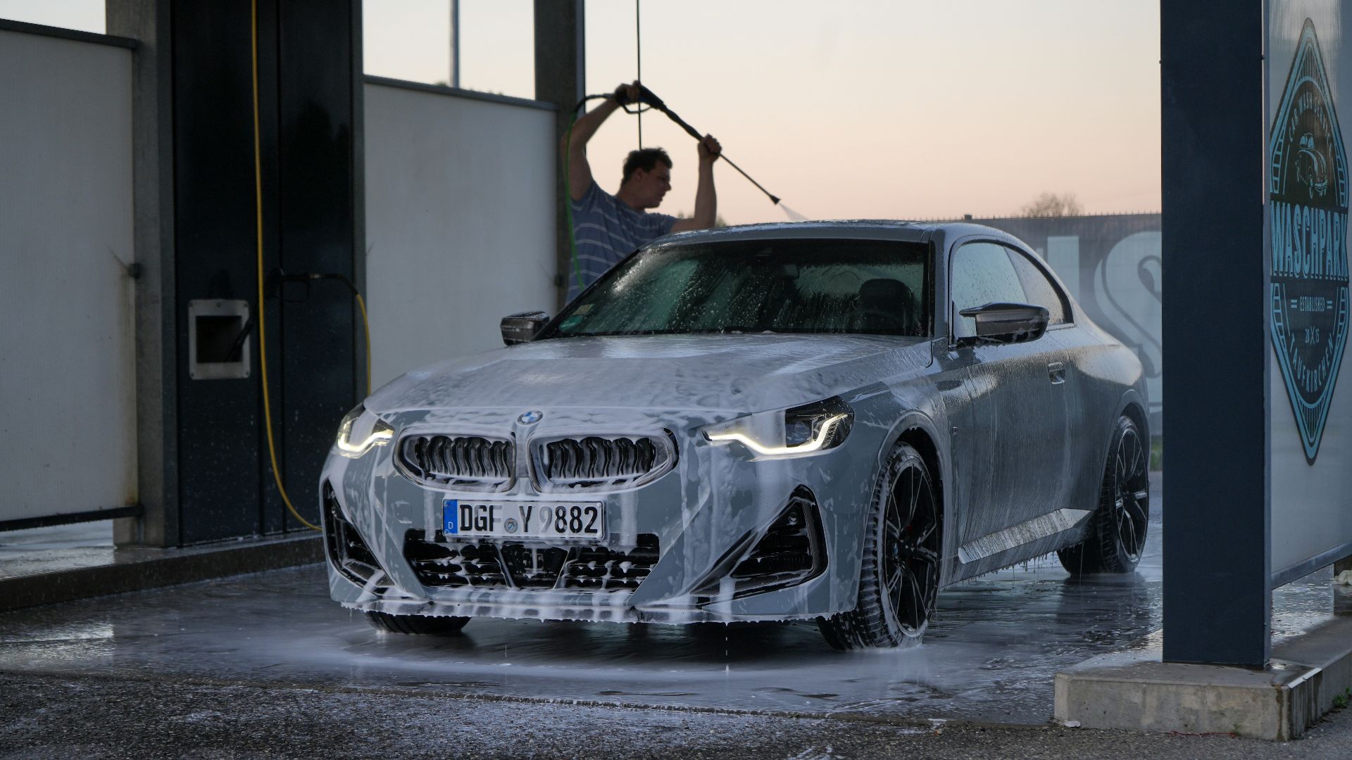 a man washing a silver car in a garage
