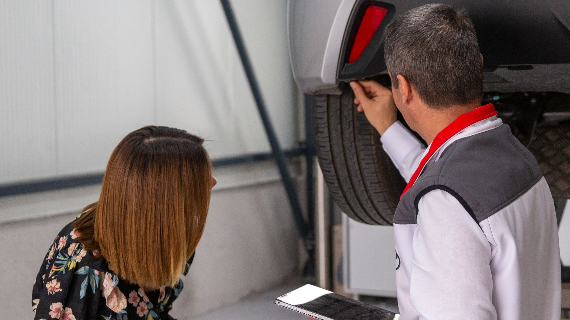 A man and a woman looking under a car