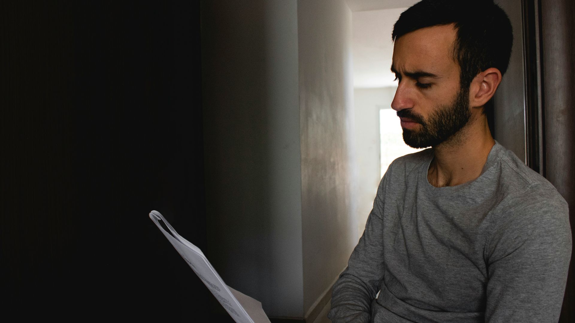 man in gray crew neck shirt holding white printer paper