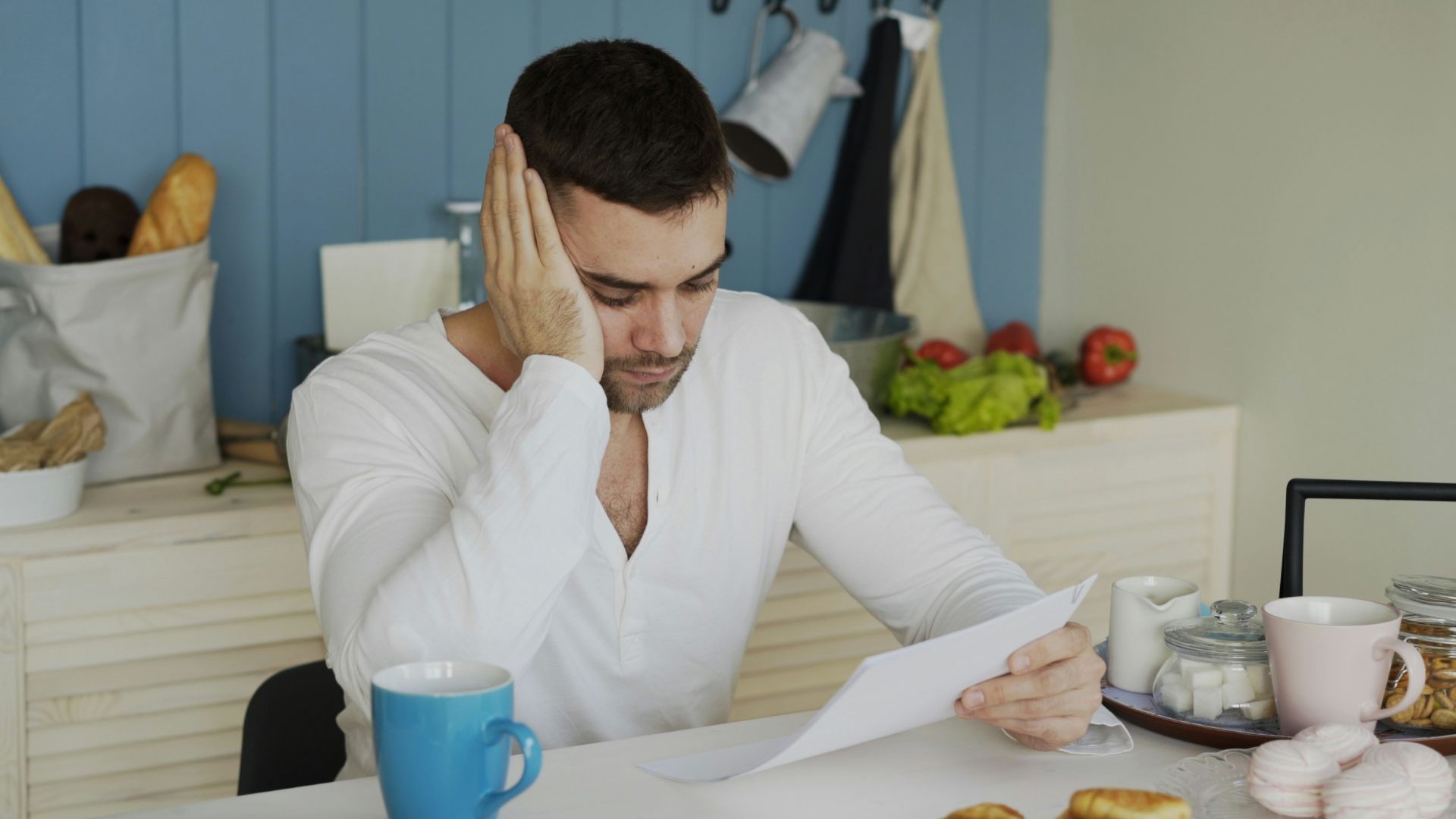 Man sitting at table reading papers with breakfast
