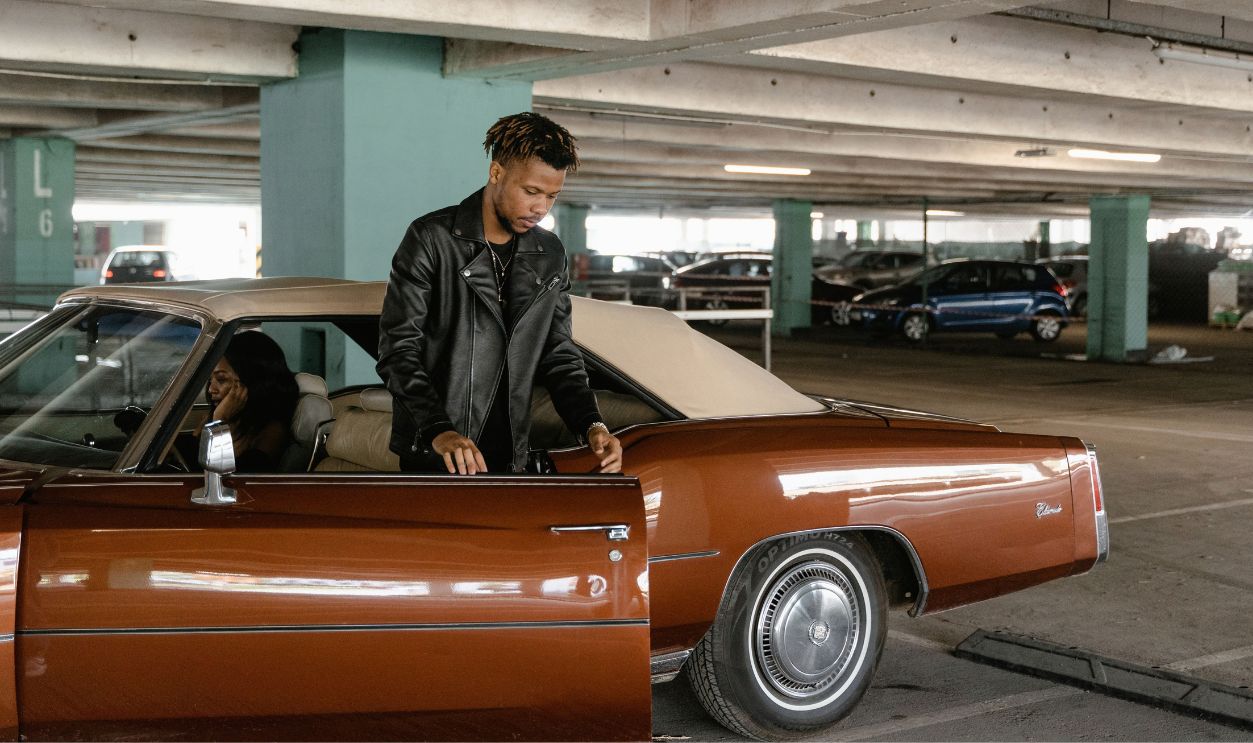 Couple standing beside vintage car in an underground parking garage