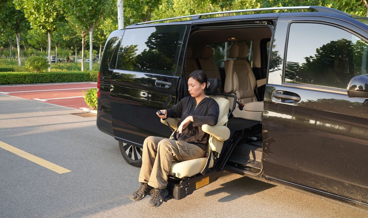 Woman using a seat lift in a black van at a parking lot with trees