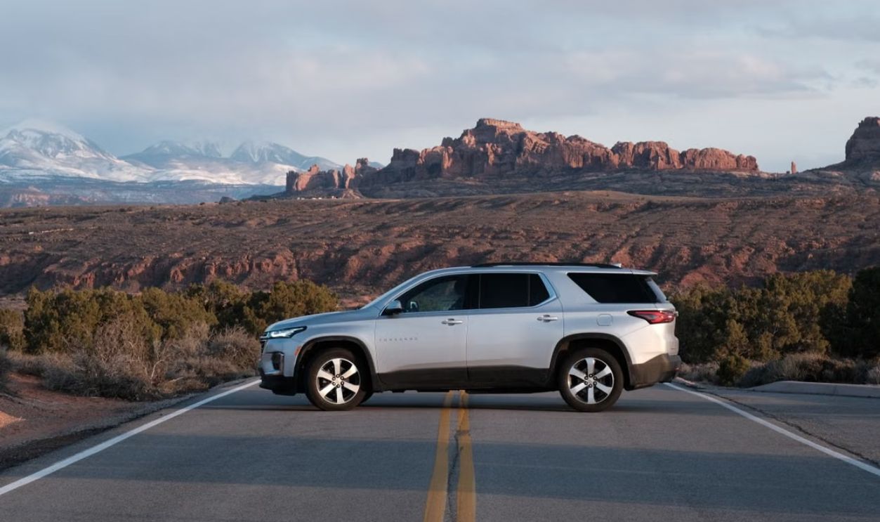Silver SUV on a road against the rugged landscape of Moab, Utah, with red rock formations in the background