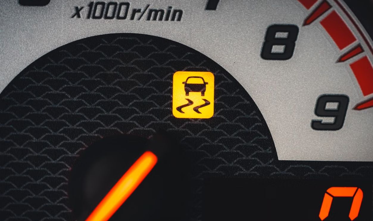 Close-up of a car dashboard showing a yellow traction control warning light