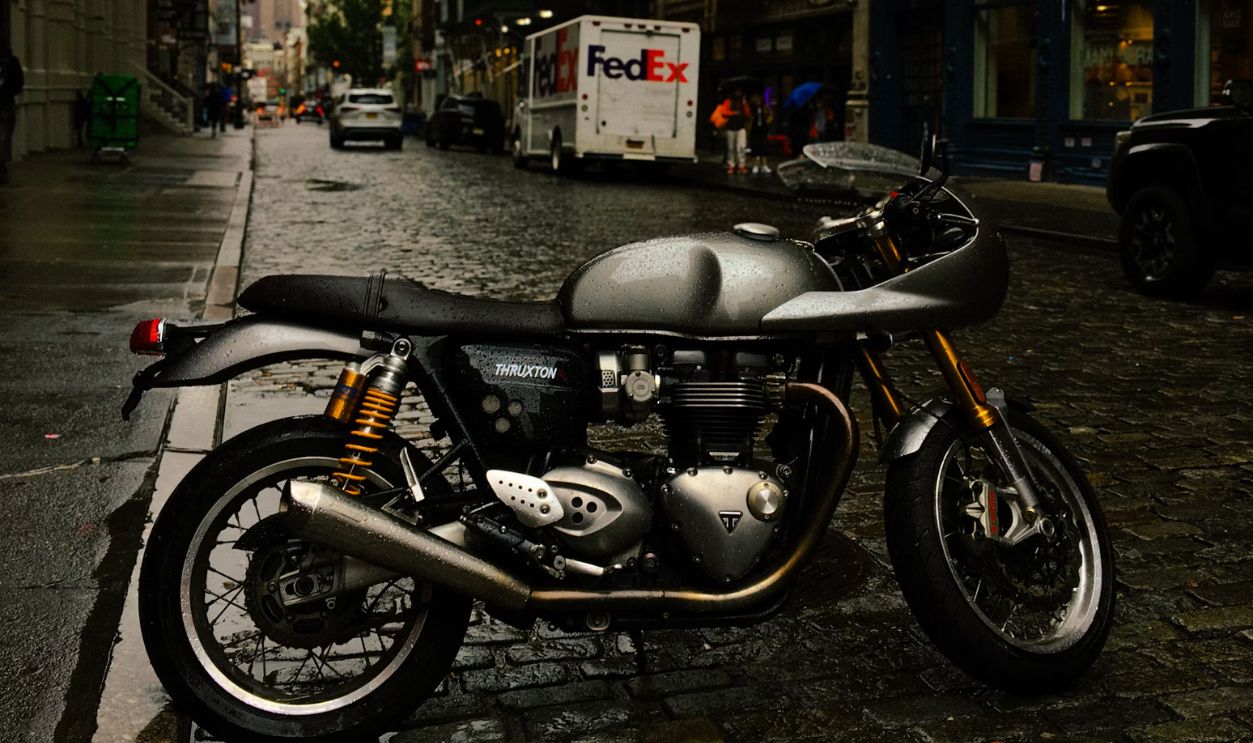 A motorcycle parked on a wet, cobblestone street