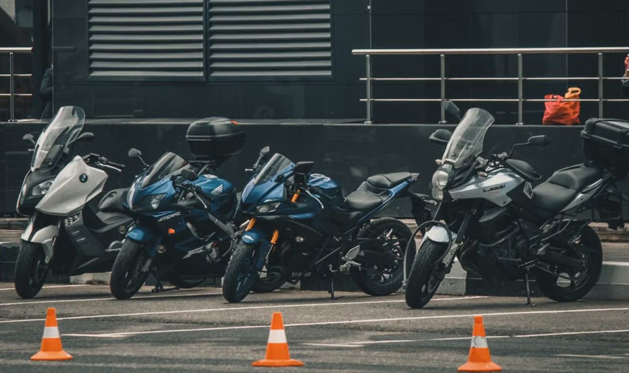 Parked motorcycles lined up in a city, an urban view with modern architecture in the background.
