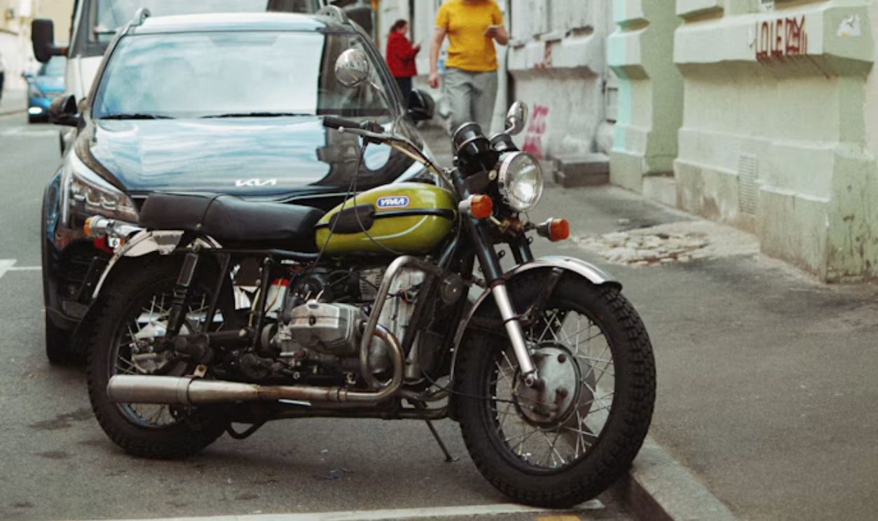 a motorcycle parked next to a car on a city street