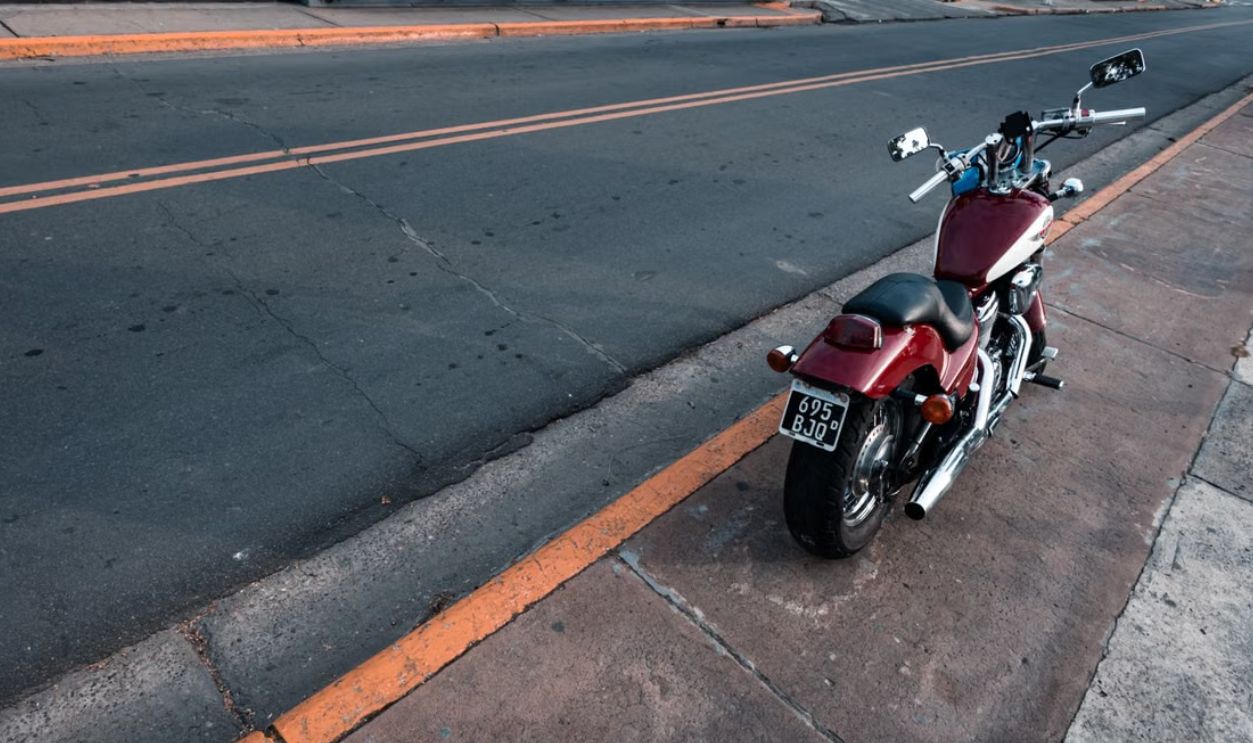 A red motorcycle parked on a city street curb in Buenos Aires, Argentina, during the day.