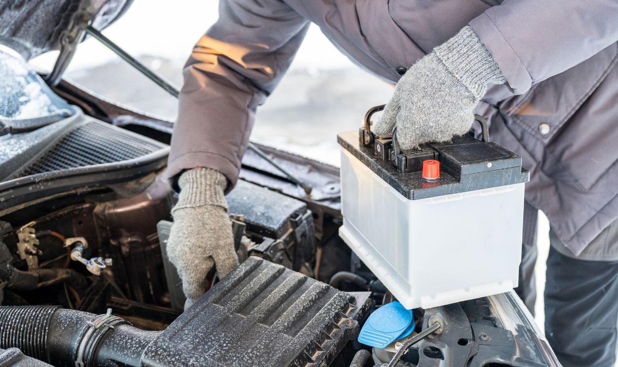 Man replacing car battery in winter cold with open hood during roadside emergency repair, emergency vehicle maintenance concept. High quality photo