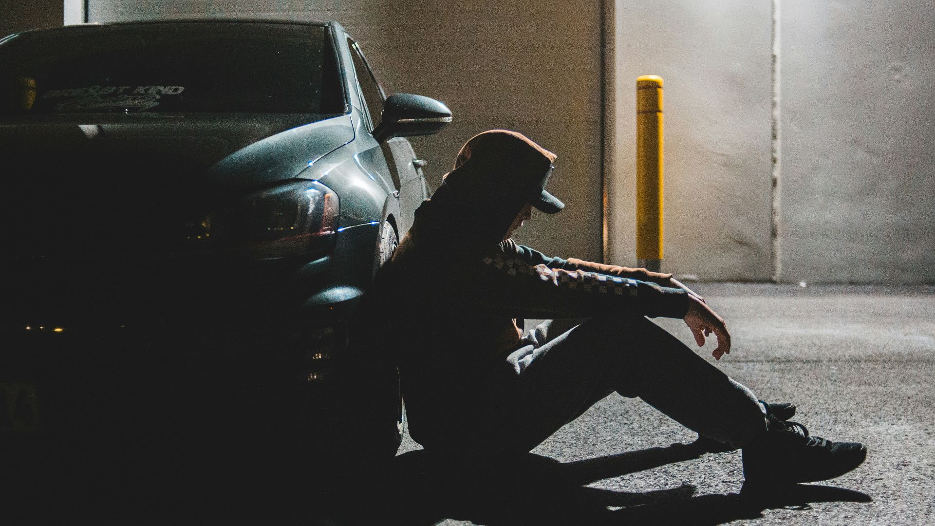 man in black jacket and black pants sitting on black car