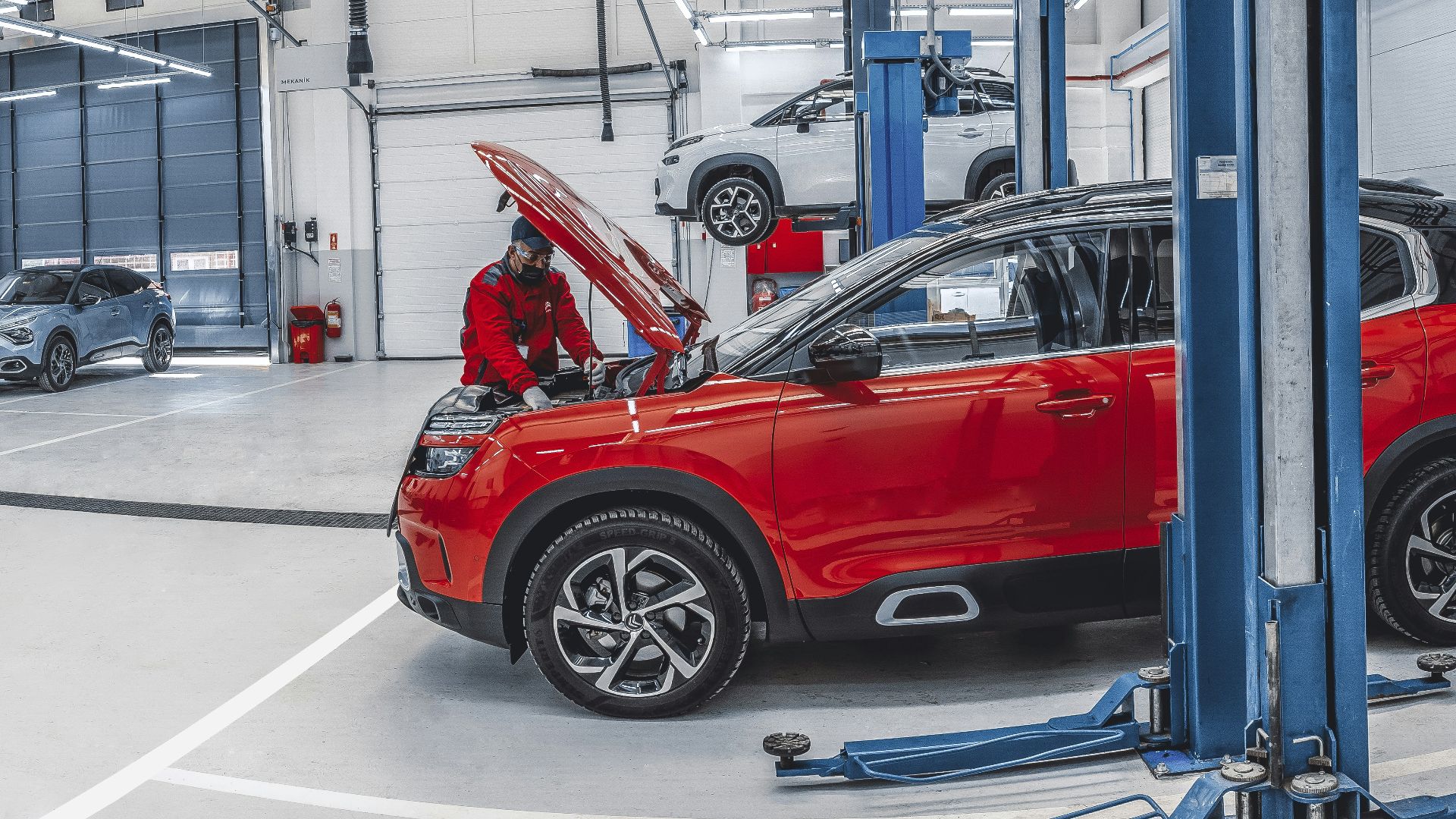 Mechanics working on cars in a bright, spacious automotive repair workshop