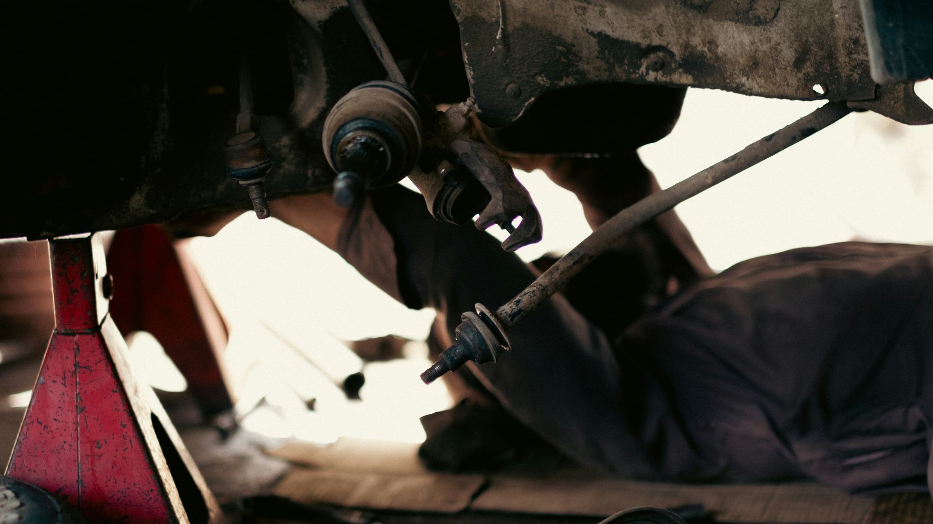 a man working on a car under a vehicle