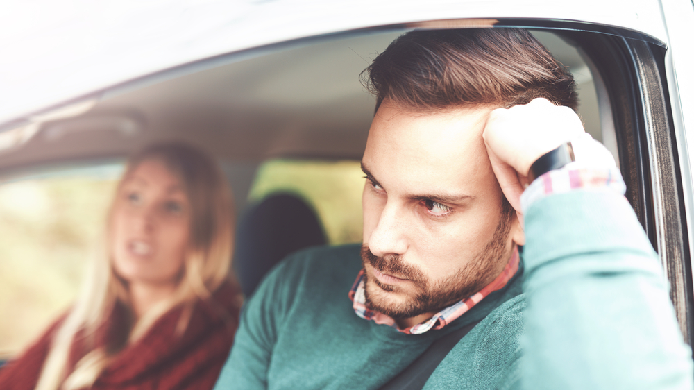Shocked man and confused woman in car having an argument