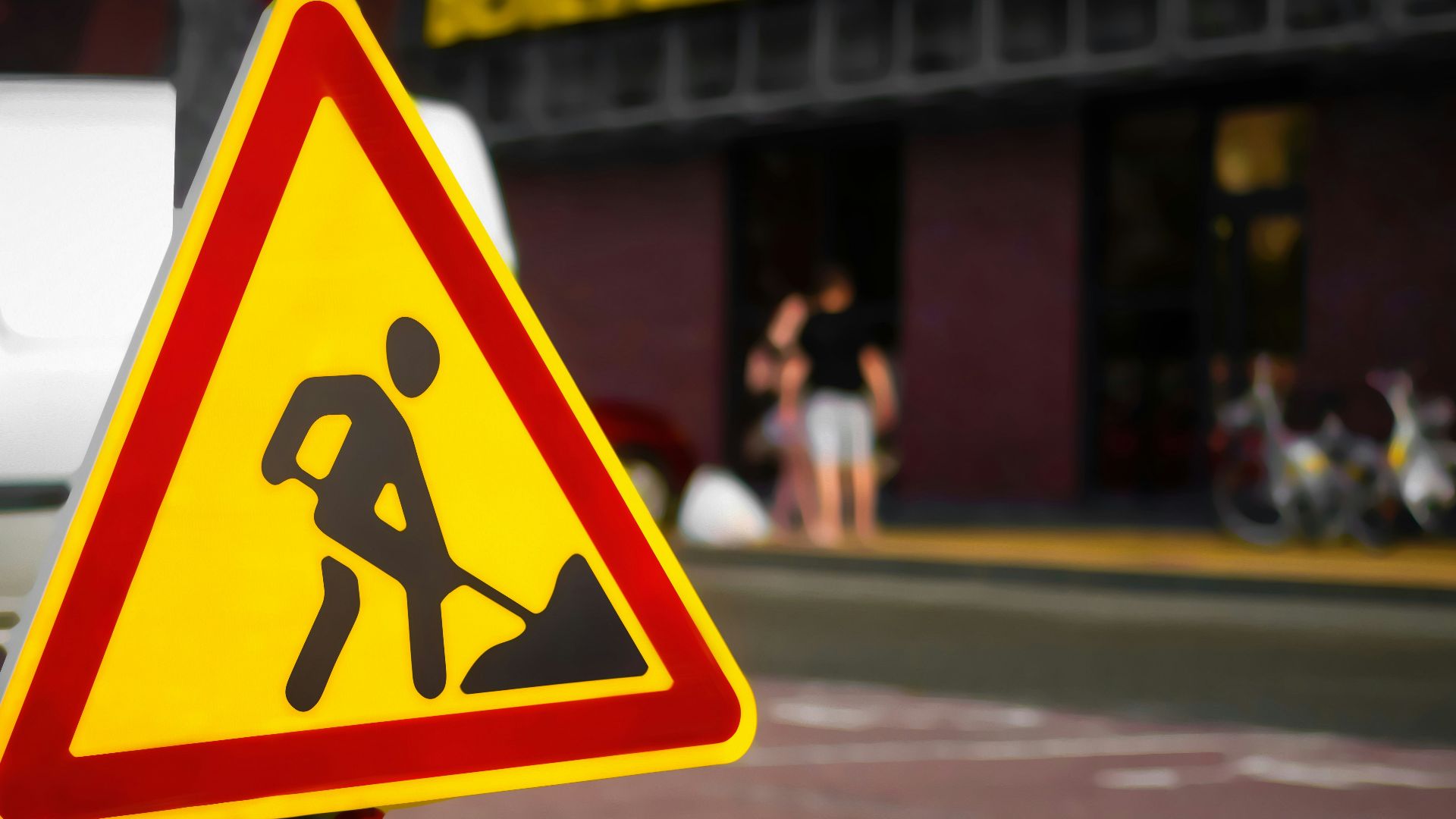 a yellow and red street sign sitting on the side of a road