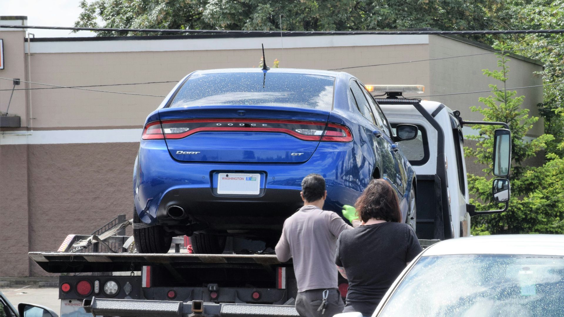 a blue car being loaded onto a flatbed truck