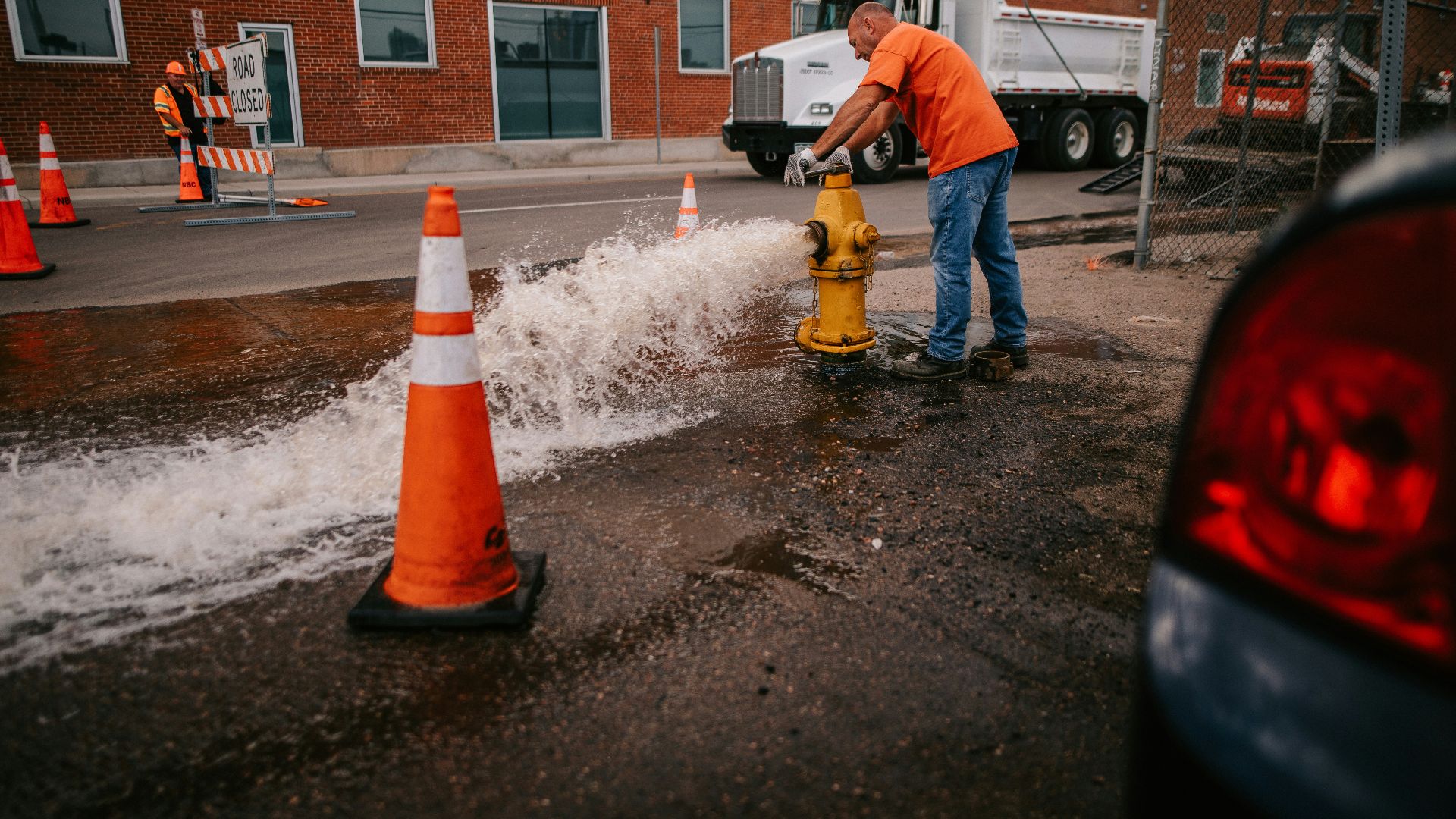a man in an orange shirt is working on a fire hydrant