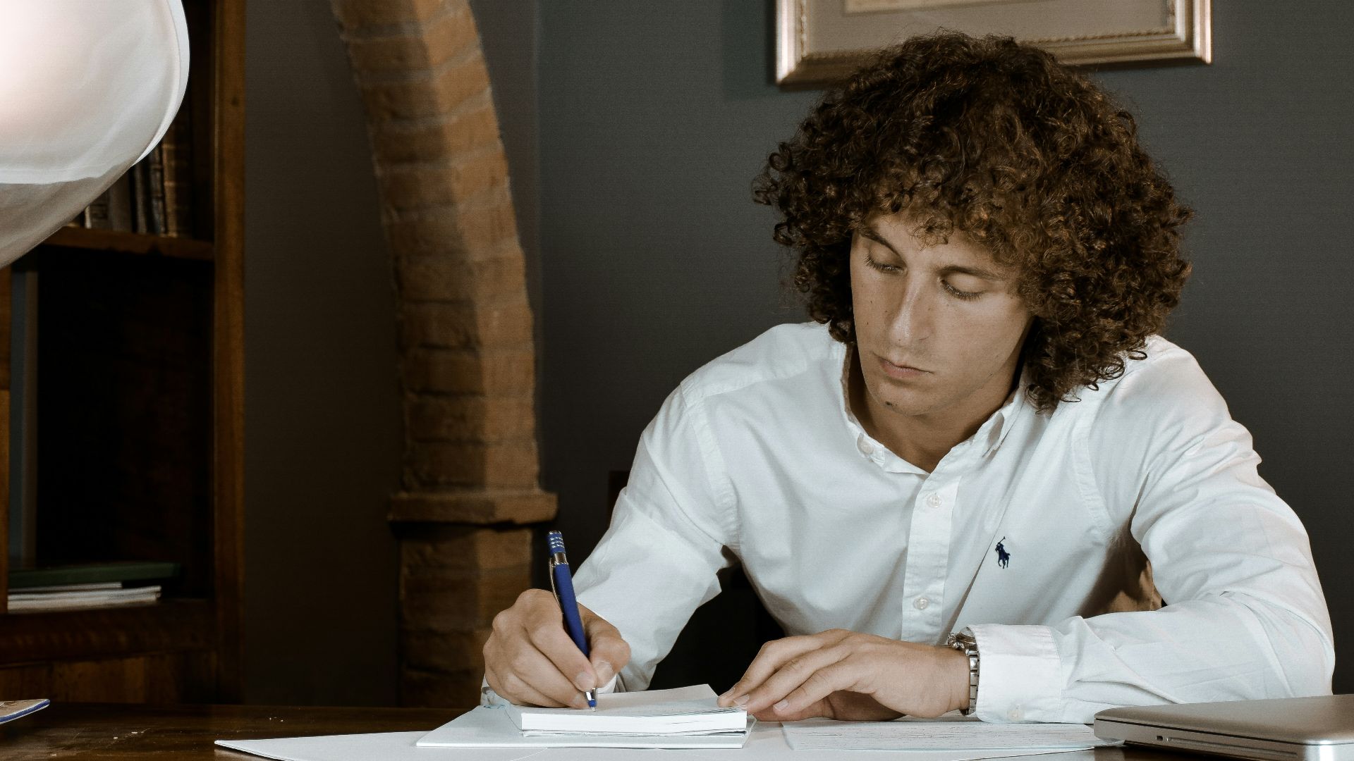 woman in white dress shirt holding pen writing on white paper
