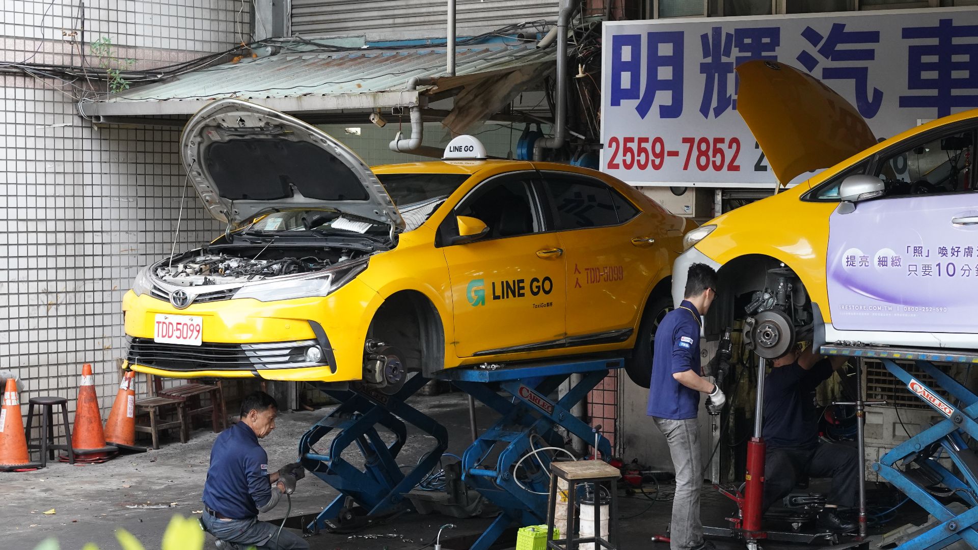 Two taxis on scissor lifts at an automotive repair shop in Datong District, Taipei.