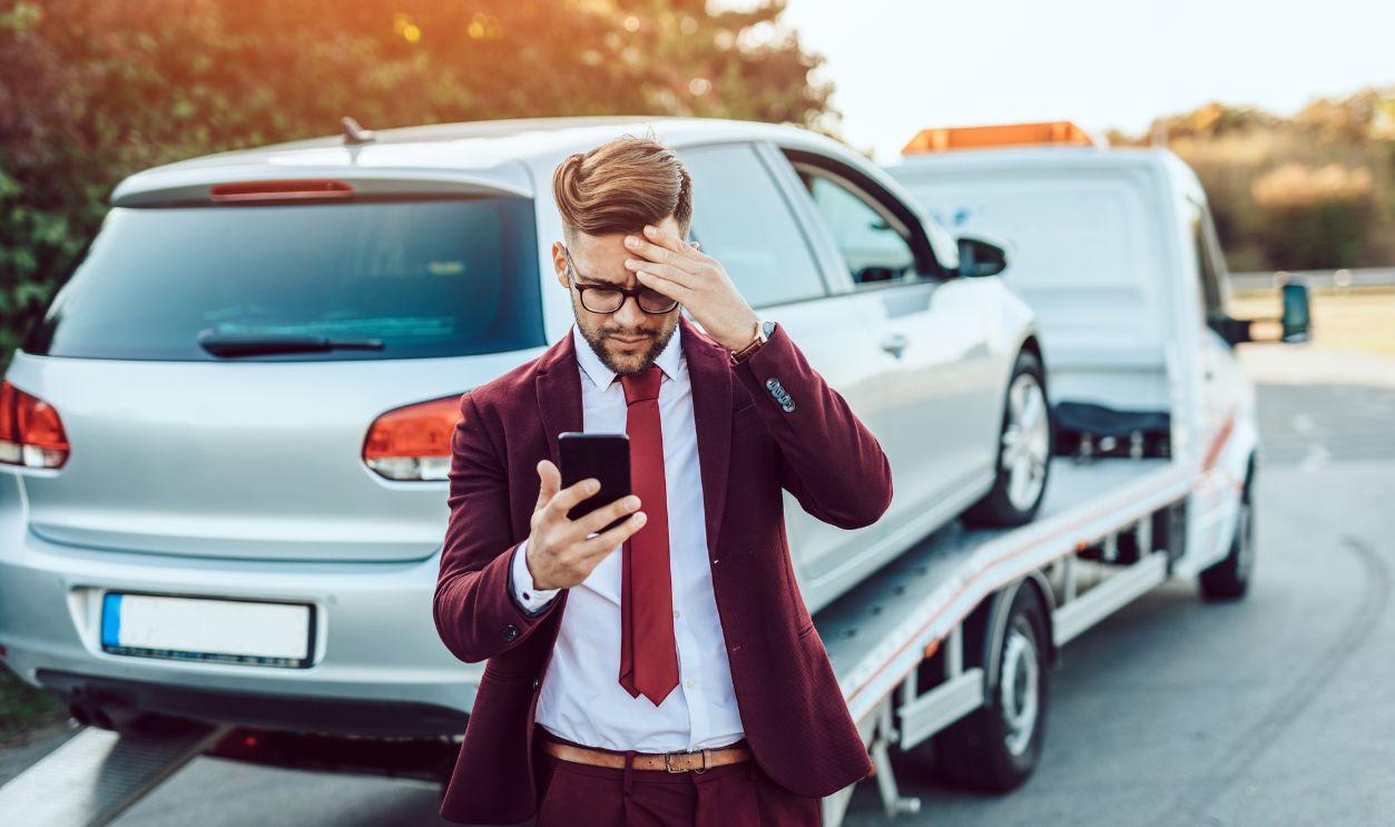 Elegant middle age business man calling towing service for help on the road. Roadside assistance concept.