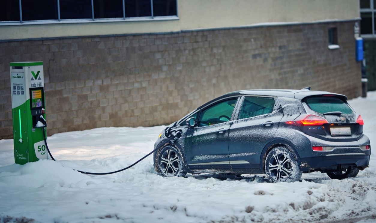 Minsk, Belarus. Dec 2022. Chevrolet Bolt EV charge car battery in winter season. Snow covered electric car GM Chevy Bolt at charging station, power supply. EV vehicle with connected charging cable