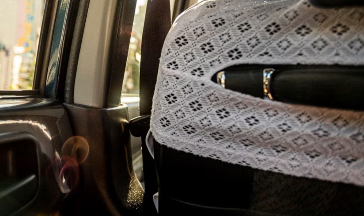 Sunlight illuminates interior of a taxi with lace seat covers, capturing a serene moment