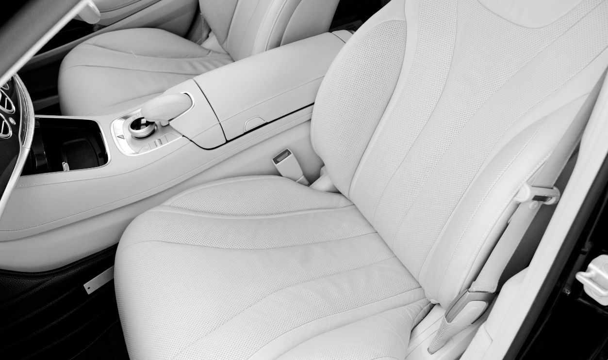 White leather interior of the luxury modern car. Leather comfortable white seats and multimedia. Steering wheel and dashboard. Automatic gear stick. Car detailing. Black and white
