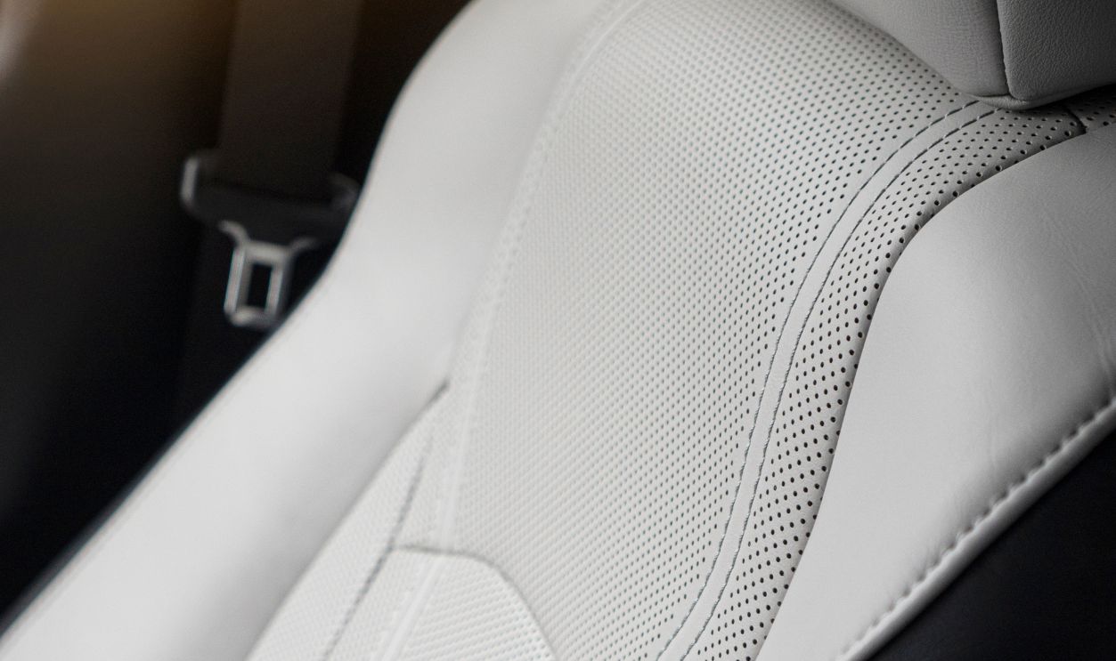 Premium car interior detail. White leather ventilated seats of modern car.