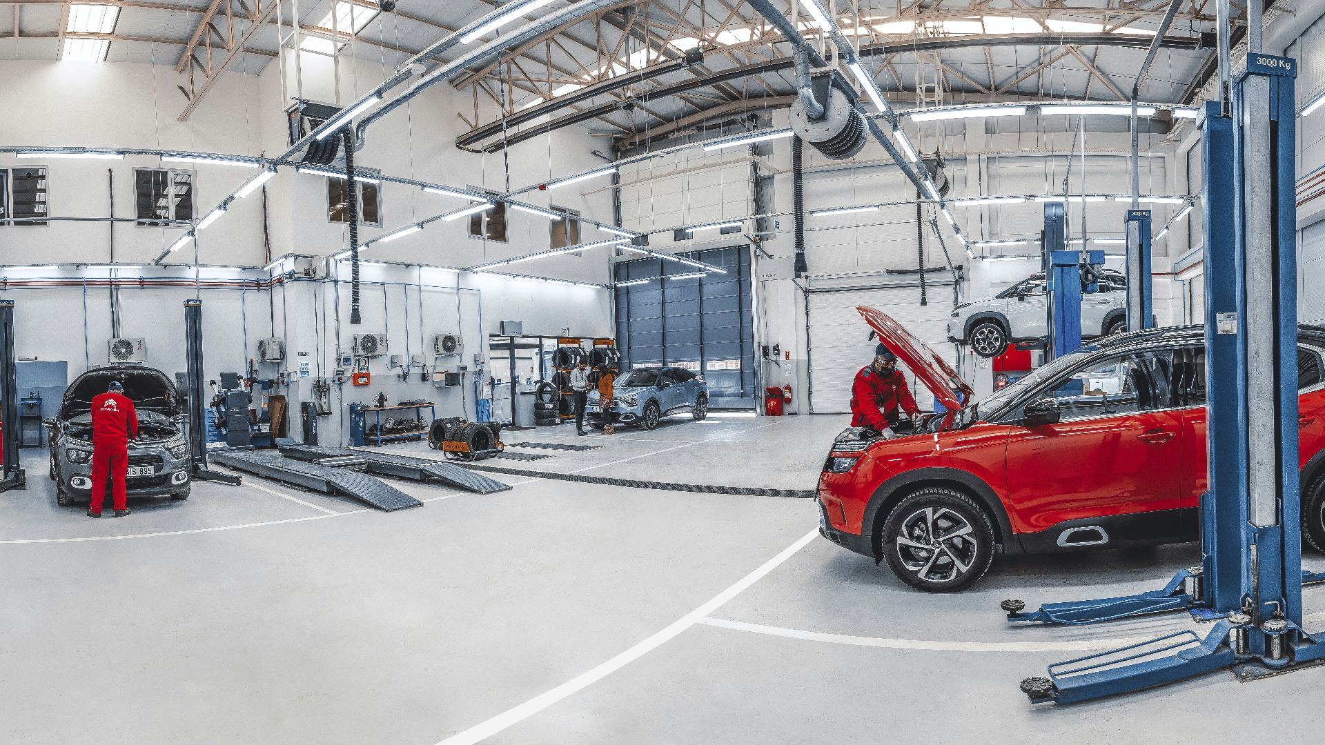 Mechanics working on cars in a bright, spacious automotive repair workshop