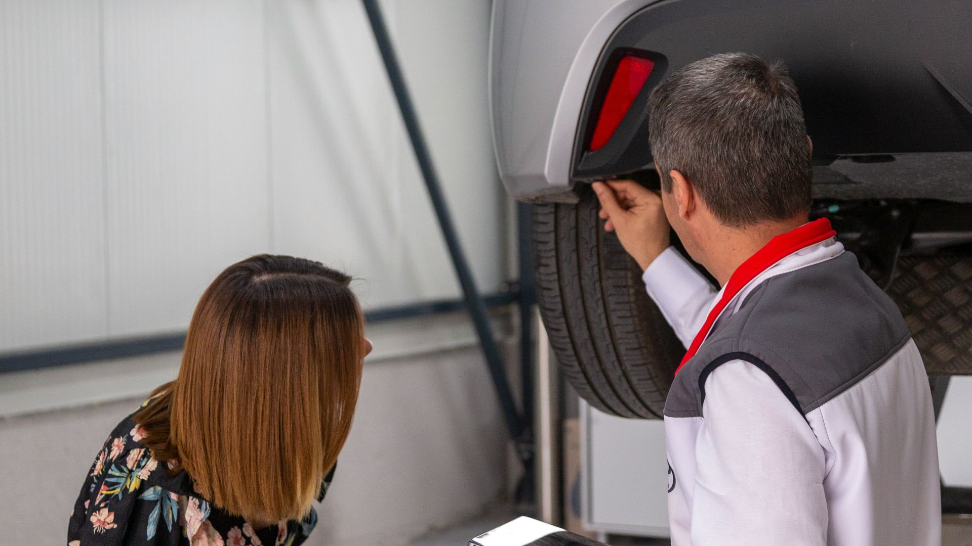 A man and a woman looking under a car