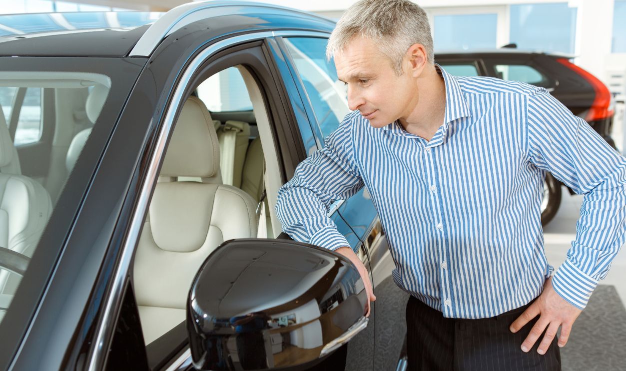 Modern insides. Mature man examining interior of a new car at the luxury car dealership businessman buying a car at the dealership showroom offer decision choosing lifestyle buying buy vehicle concept