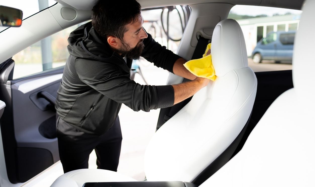 Adult male cleaning car interior with yellow cloth