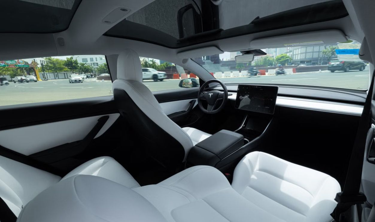 Elegant interior of an electric car featuring luxurious white leather seats and a panoramic view