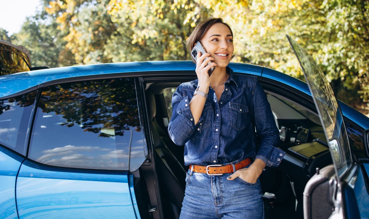 Woman talking on the phone and standing by her car