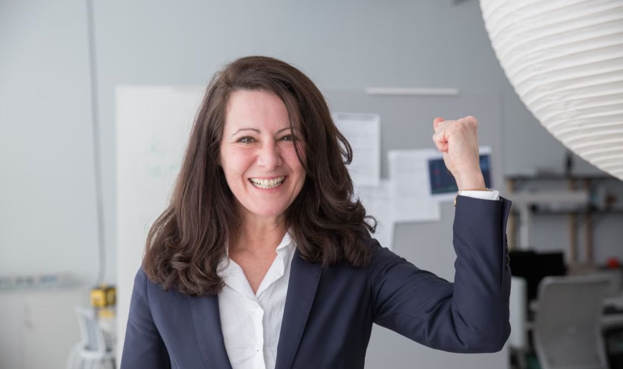 Smiling businesswoman in a smart suit celebrating a success in the office.