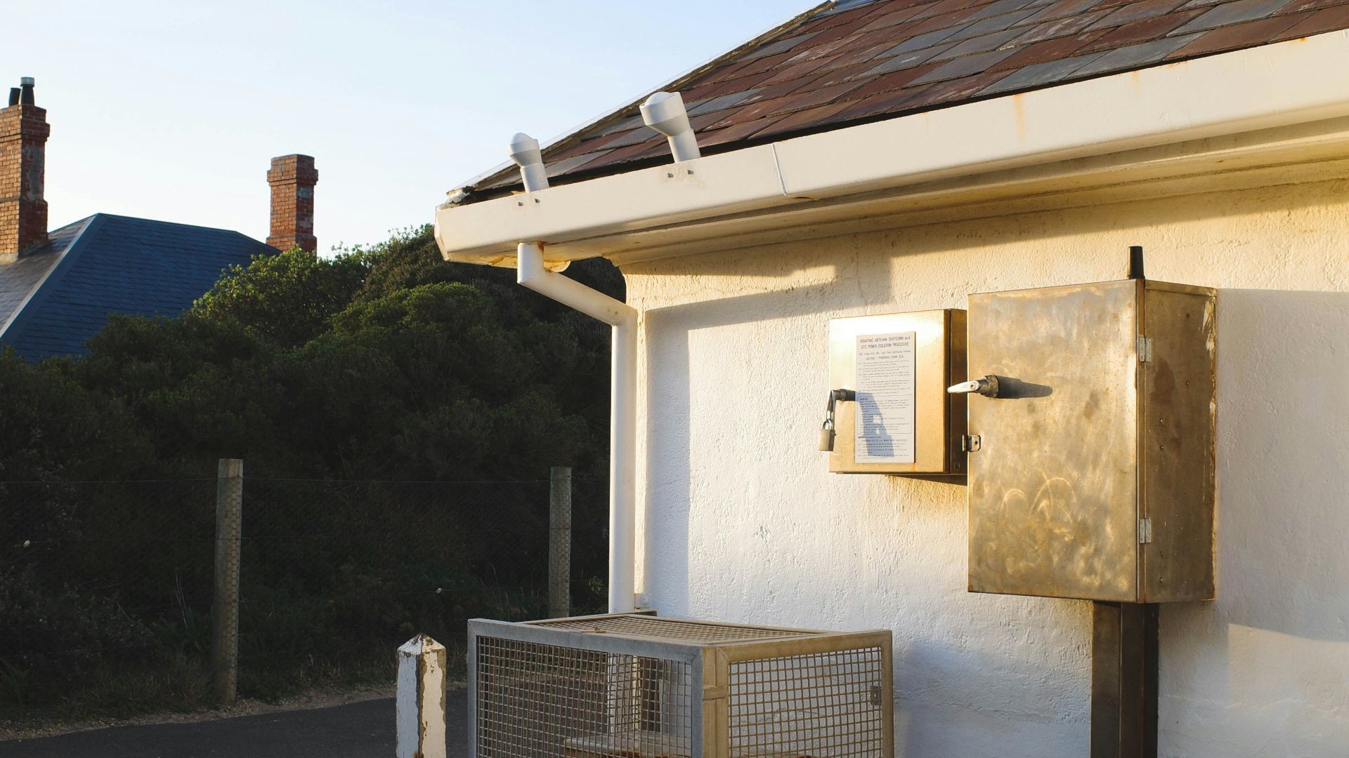 Golden box and white gutter on building exterior at sunset