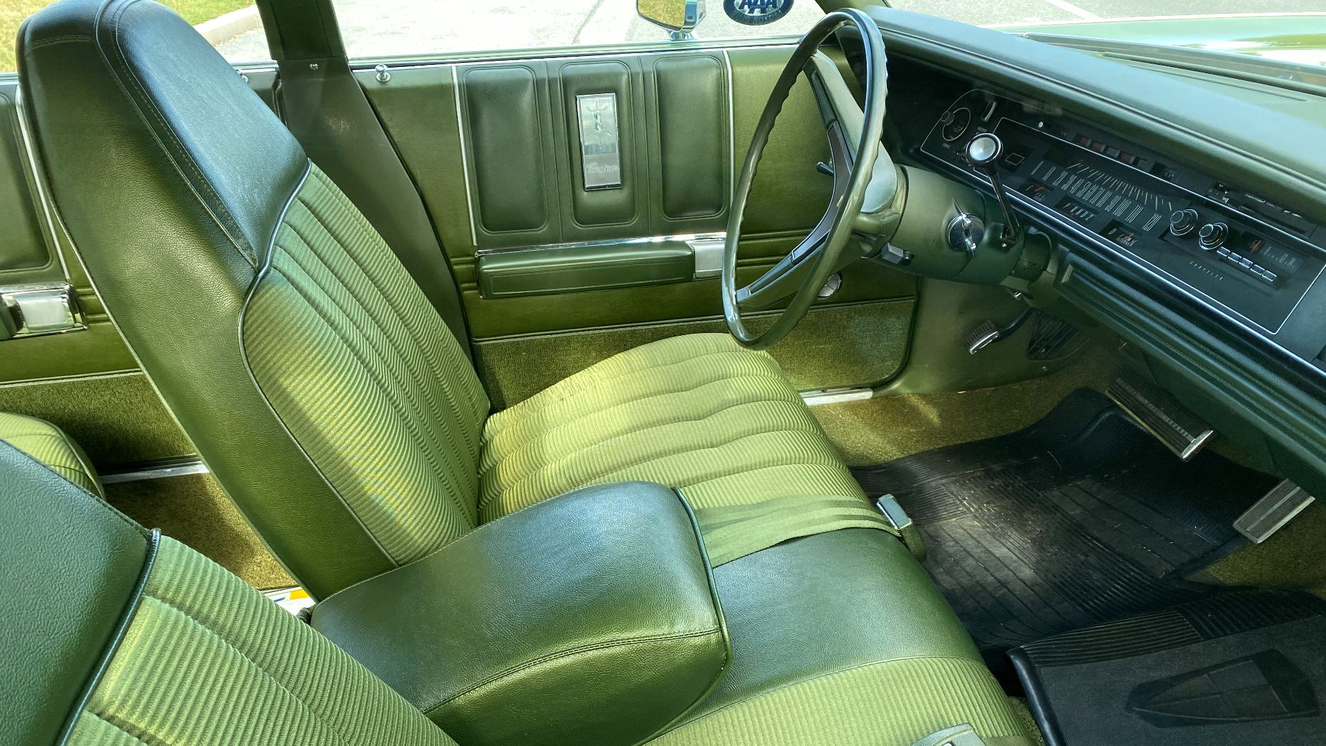 Interior of a 1971 Chrysler Newport Custom 4-door Sport Sedan. Upholstery in green, front bench seat with a center armrest. Photographed at the 2019 AACA Hershey swap meet in Pennsylvania