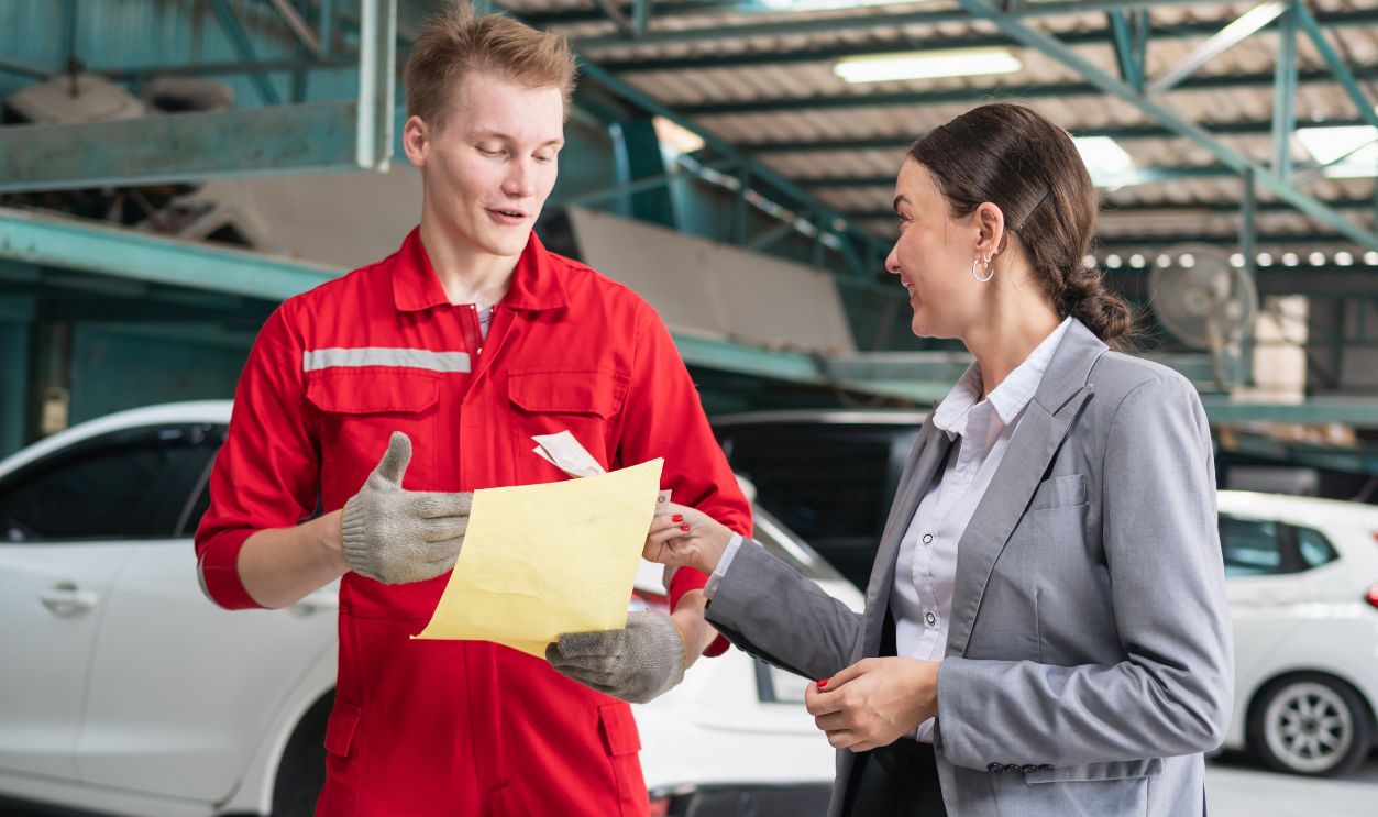 Shutterstock - 2293382923 - Female customer paying mechanic with cash at the repair garage.