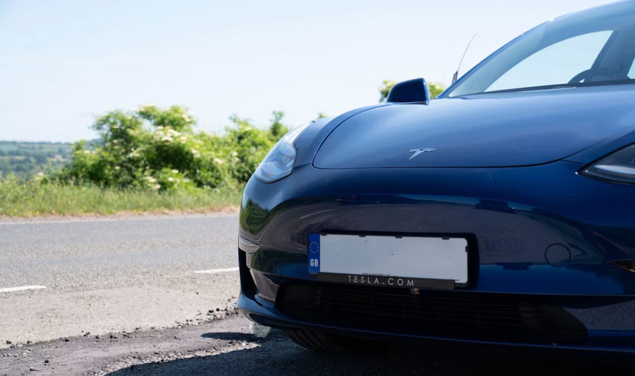 Blue tesla car parked on the side of the road