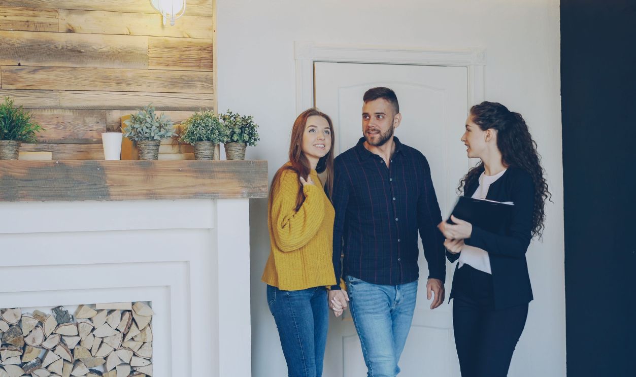 Young couple meeting with real estate agent inside cozy home, exploring purchase options.