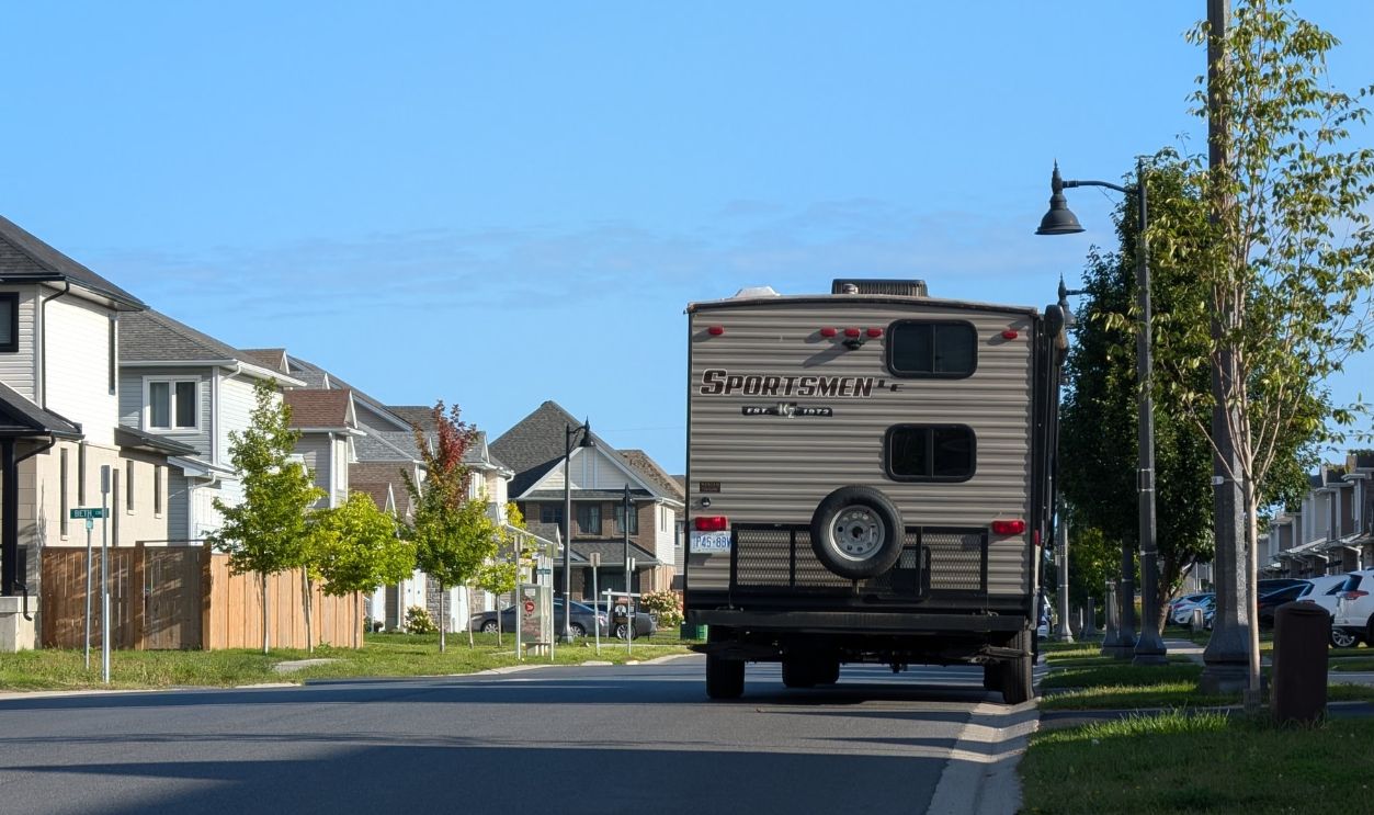 Sunny day view of a suburban street with a camper in Kingston, Ontario, Canada