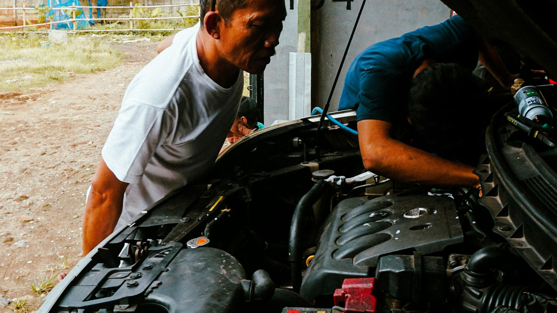 a man working on a car engine in a garage