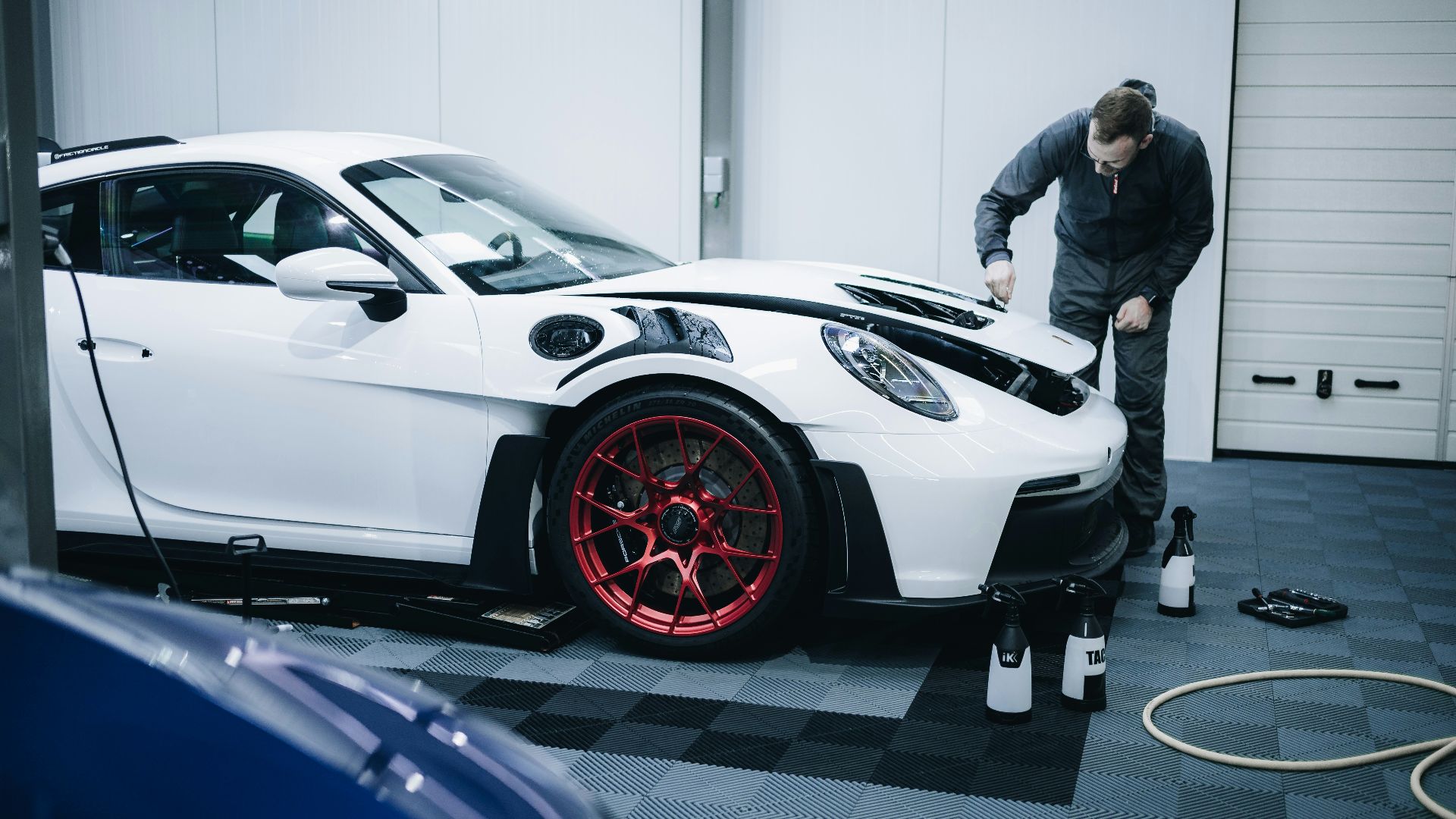 a man working on a white car in a garage