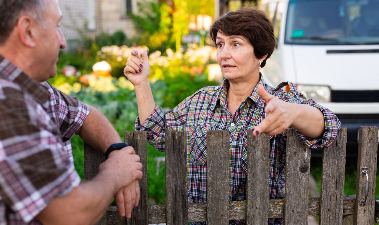 neighbors middle aged man and woman chatting near the fence in the village