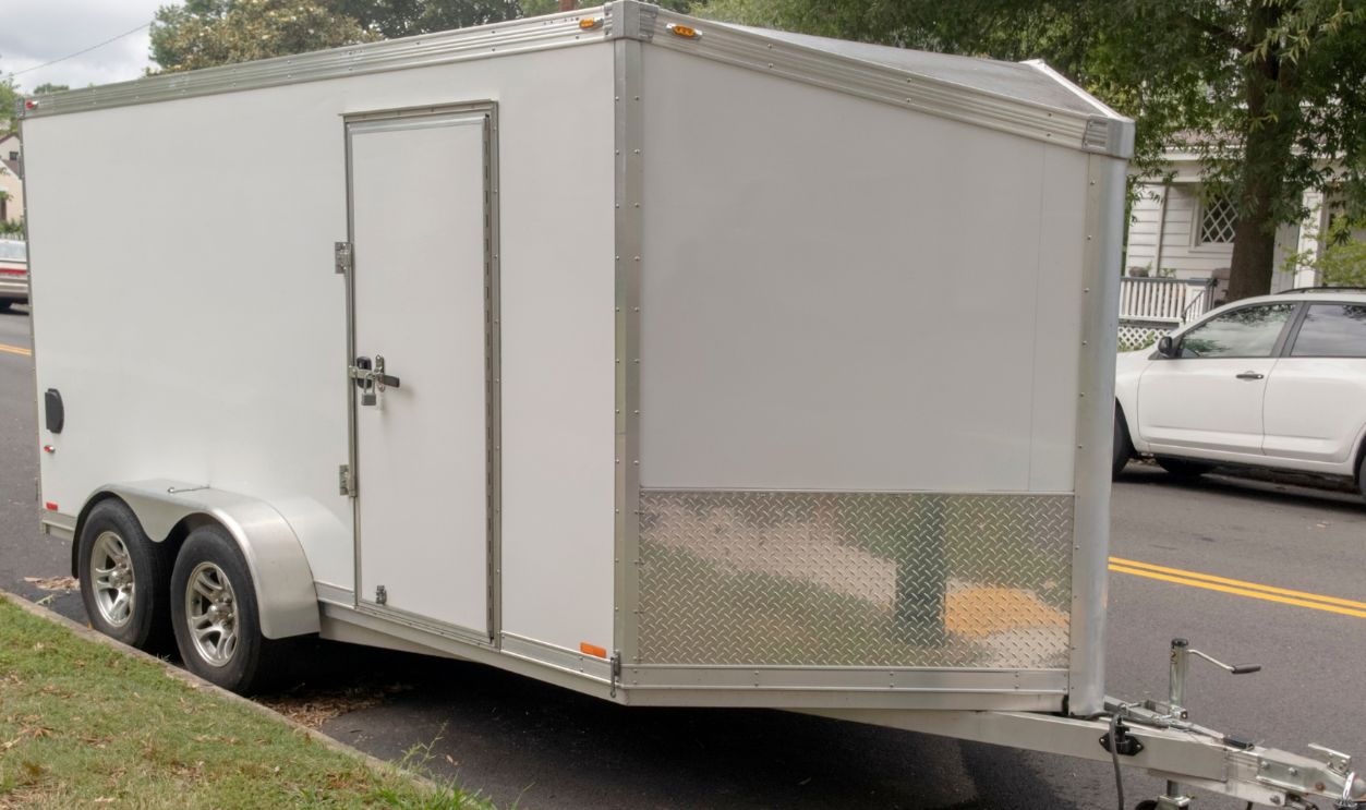Side and front view of construction equipment trailer parked on residential neighborhood street.