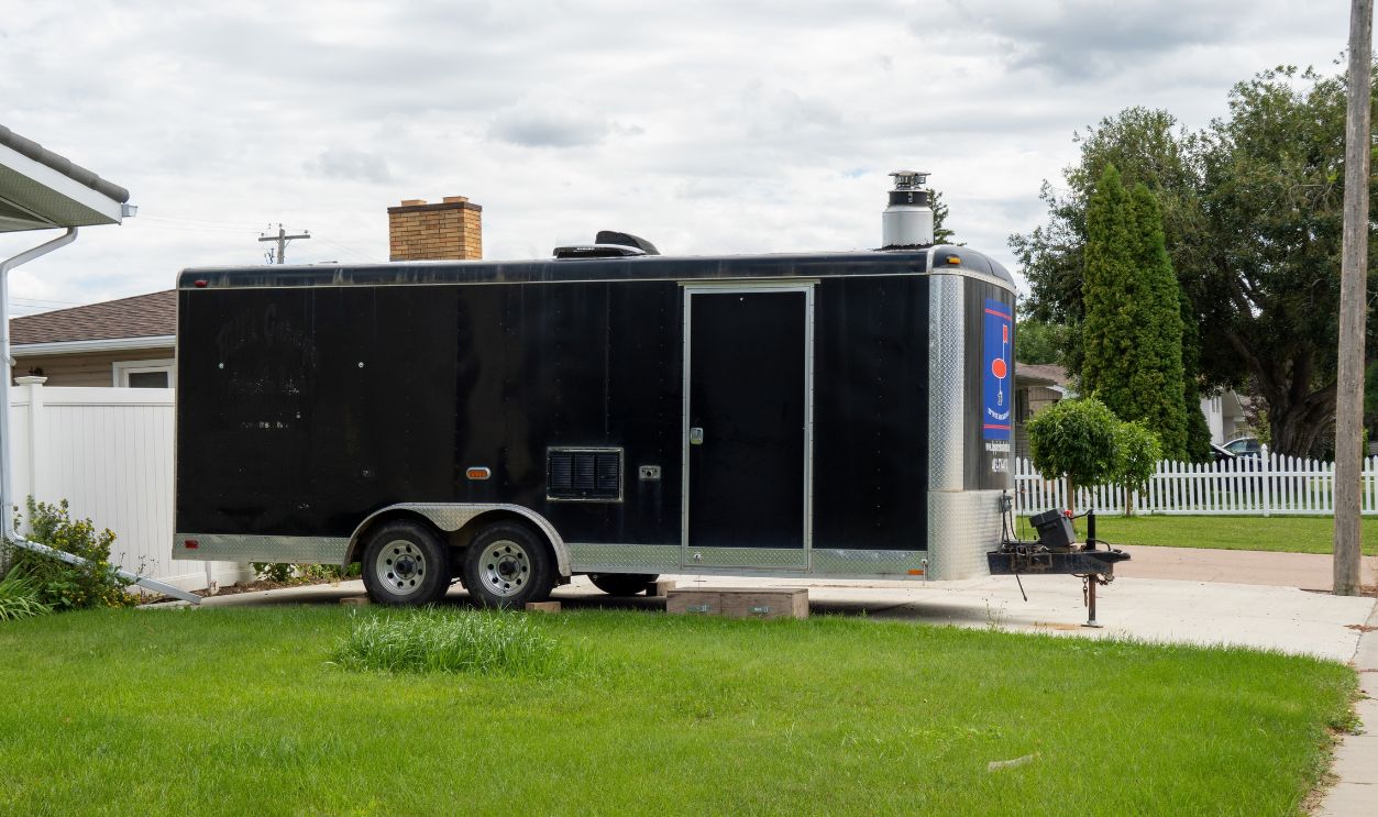 Brooks, Alberta - August 11, 2025: The enclosed trailer is parked in the yard of the house