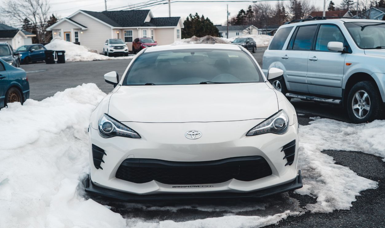 White Toyota parked in a snow-covered city street on a winter day.